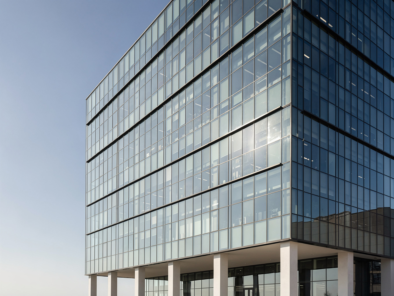 Modern glass and steel government building reflecting the blue hour sky